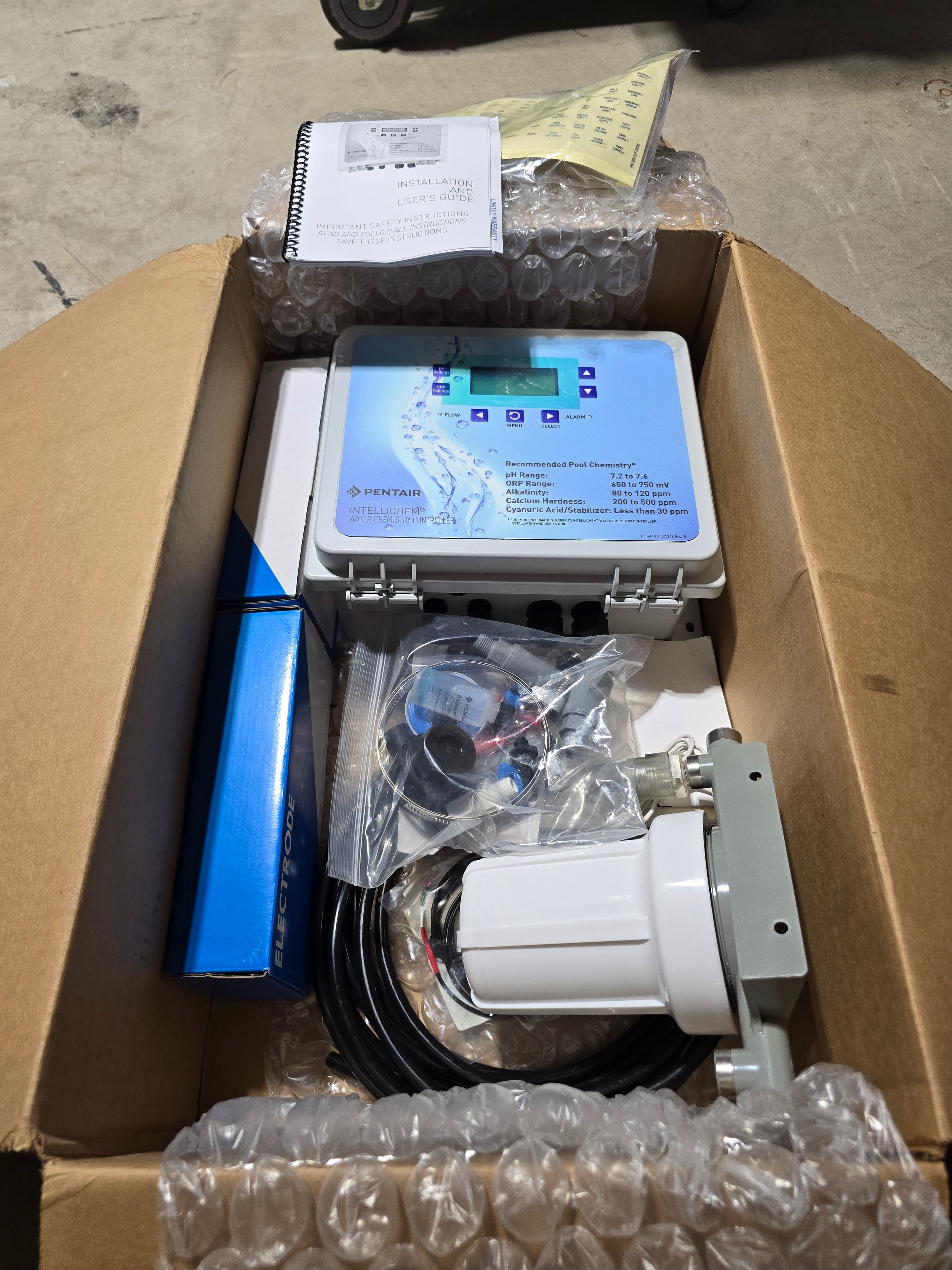 Pentair IntelliChem 521357 box open — controller unit, flow cell, electrode box, probes, and installation hardware